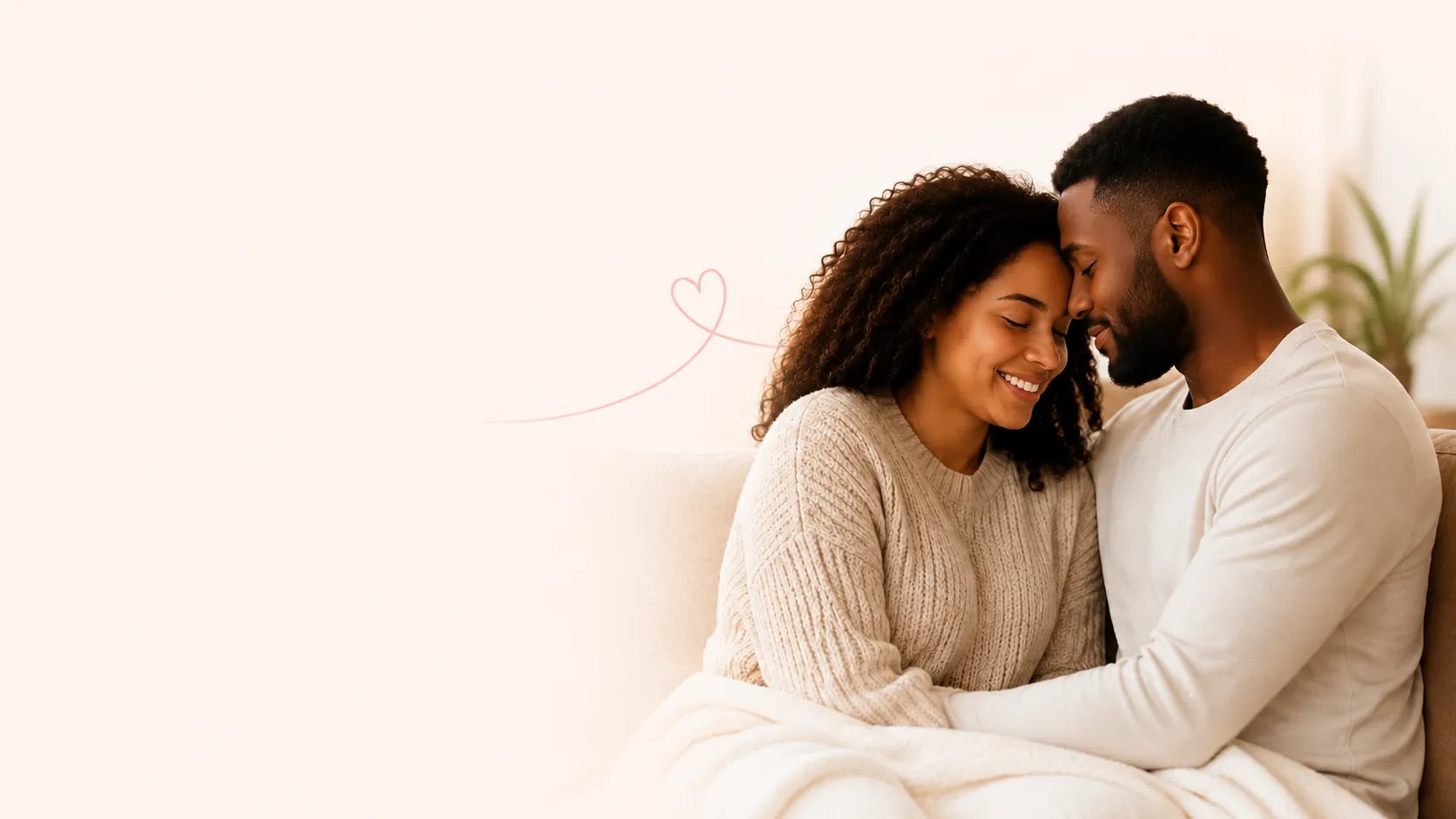 A couple sitting close together on a sofa, foreheads touching, smiling with their eyes closed.